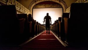 Corredor de cinema com tapete vermelho e poltronas, clima de Hollywood