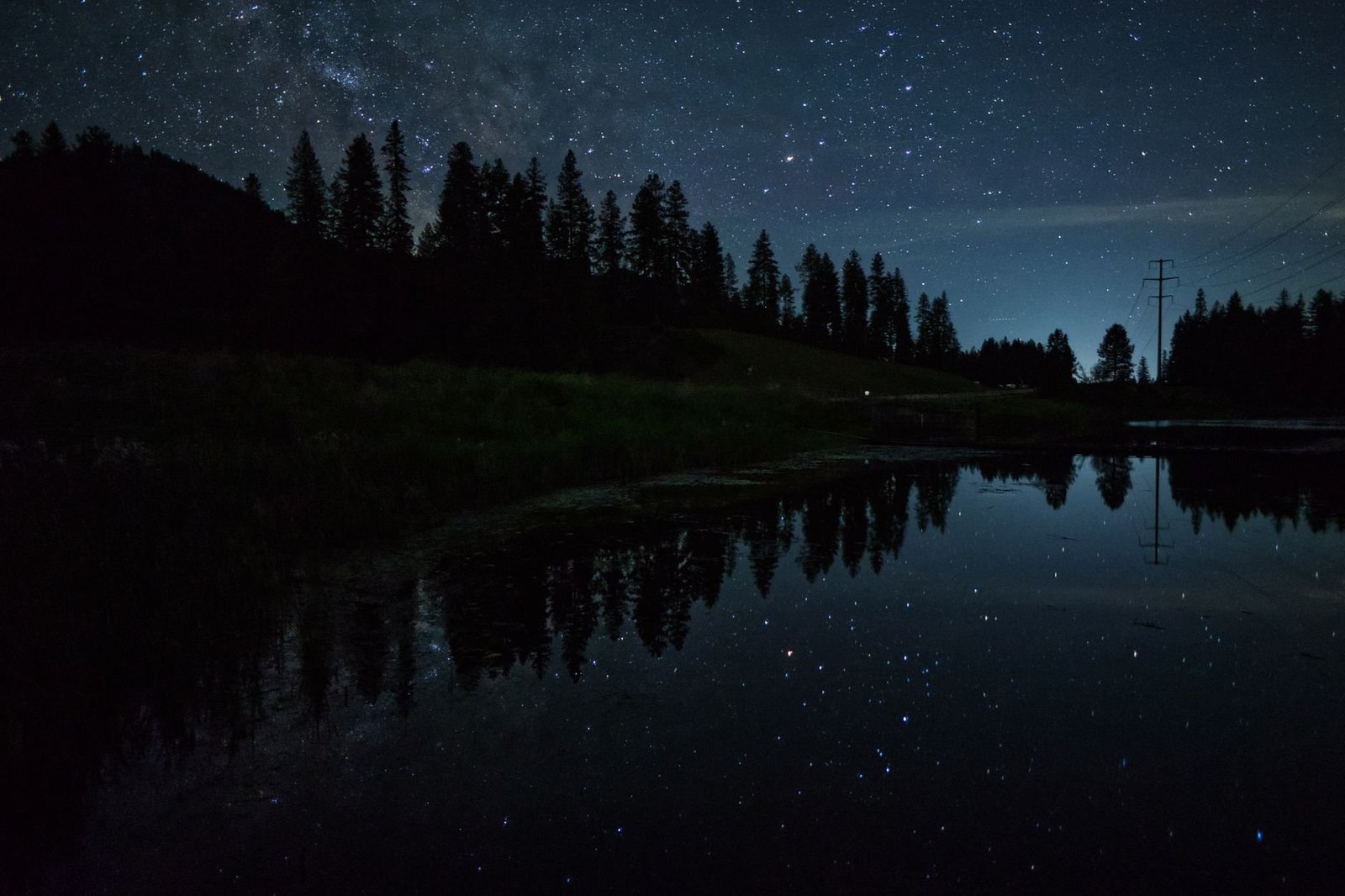 Lago Negro à Noite: Vale a Pena no Natal Luz? 3 Lago noturno cercado por floresta escura com reflexo das árvores na água