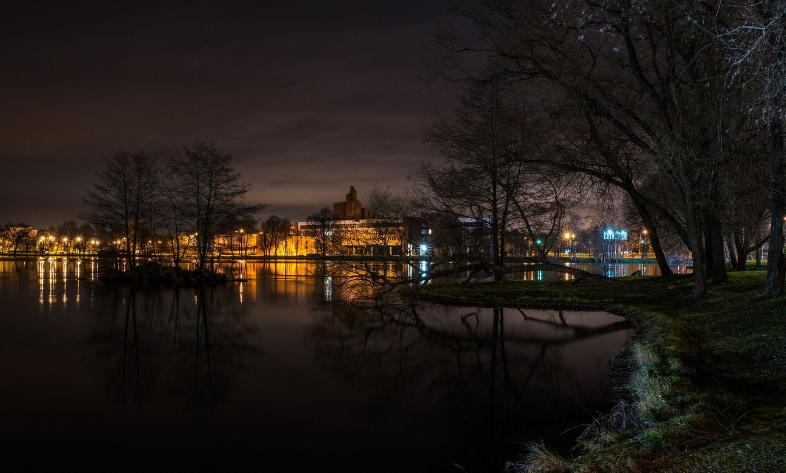 Lago Negro à Noite: Vale a Pena no Natal Luz? 2 Lago tranquilo à noite com reflexo de luzes na superfície escura da água