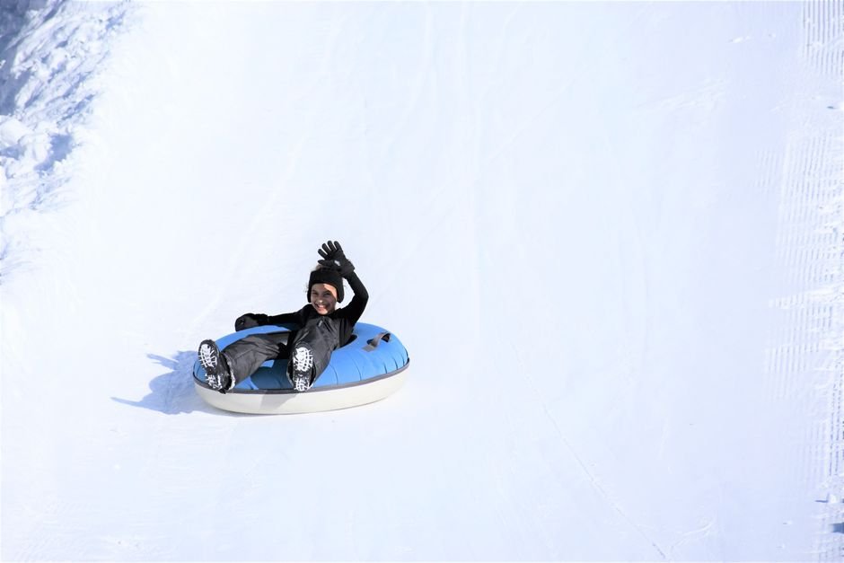 Snowland Gramado: Vale a Pena? Guia Completo 2 Criança se divertindo em descida de boia na neve, atração de snow tubing