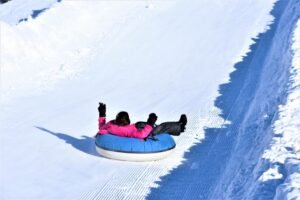 Pessoa descendo em boia em uma pista de neve, ilustrando atração de snow tubing