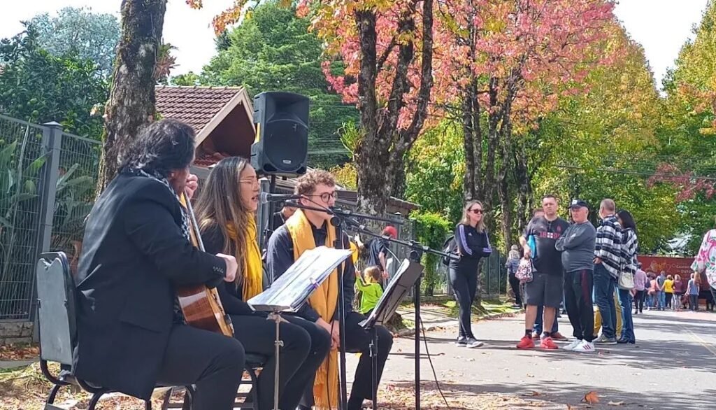 3º Festival Caminhos de Outono de Gramado Música e arte 3 Pessoas observando as apresentações de bandas na rua