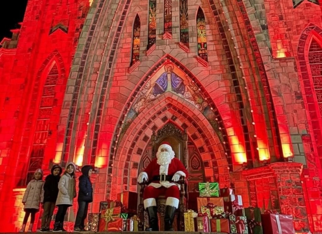 Sonho de Natal Canela 2025: Programação Completa 4 Crianças e Papai Noel em frente a Catedral de Pedra.