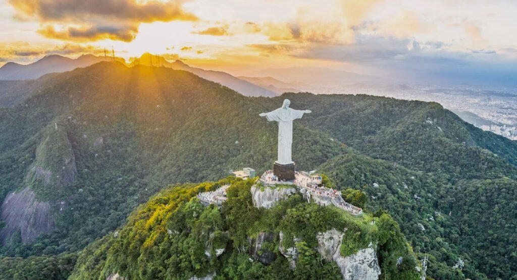 Conoce el Cristo Redentor: Entradas, consejos e historia del símbolo de Río 1 Cristo Redentor con los brazos abiertos, foto vista desde arriba, al fondo la puesta de sol.