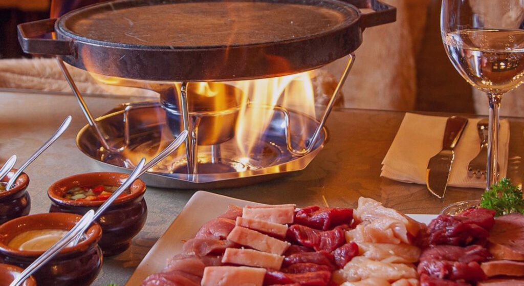 Onde comer fondue em Gramado? Confira essas opções incríveis! 1 Fondue com carnes ainda esperando para serem assadas e consumidas