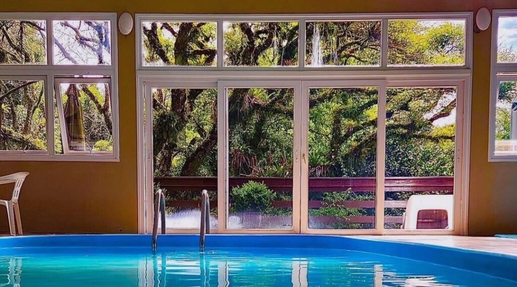 Onde se Hospedar em Gramado? 5 Sugestões de Hotéis 5 Piscina interna do Hotel Fioreze Quero Quero, pela janela uma árvore no jardim