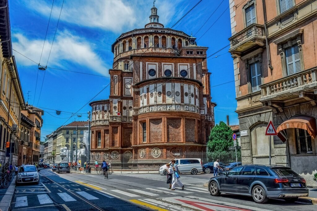 Duomo de Milão: Guia Completo para Sua Visita Inesquecível 4 Rua de Milão, dia de sol com pessoas atravessando a rua.