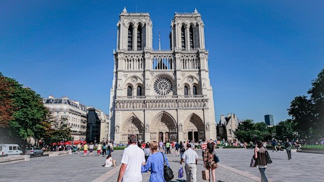 Catedral de Notre Dame: História, Incêndio e Reabertura em 2024 5 A foto mostra pessoas no pátio em frente a Notre Dame. Dia de sol. Ceu limpo e claro.