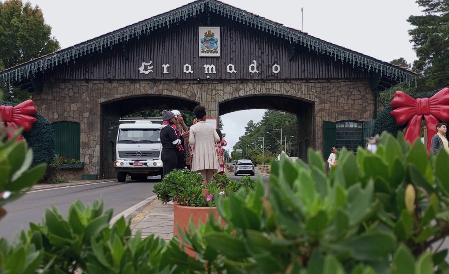 Atrações Gratuitas em Gramado e Canela 8 Pórtico de Gramado com pessoas tirando fotografias enquanto os carros passam
