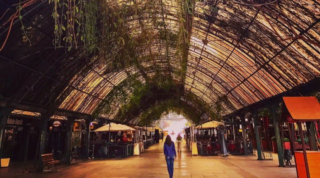 Gramado: Roteiro Perfeito com a Catedral de Pedra como Guia 2 Pessoa caminhando na Rua Coberta de Gramado, foto em tons de laranja trazendo clima melancólico