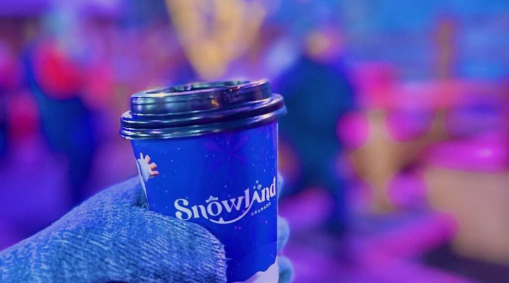 Snowland Gramado : tout ce qu'il faut savoir avant d'y aller 4 Personne avec des gants tenant un gobelet de café avec le logo du Snowland