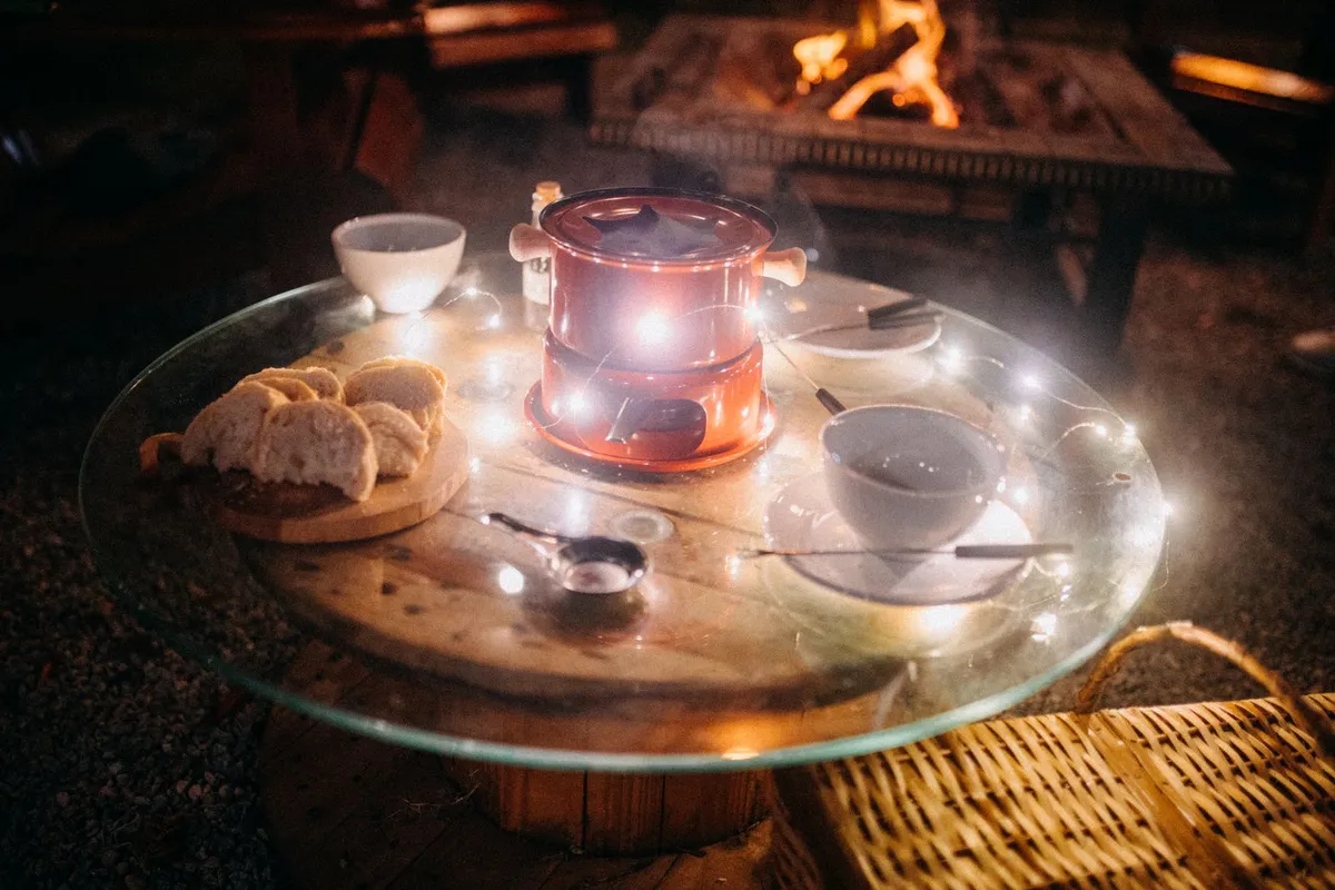 Fondue em Gramado: preço do rodízio e casas sem reserva 1 Panela de fondue sobre rechaud aceso em mesa à noite